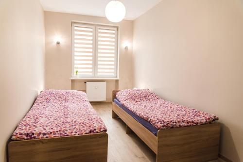 2 camas en una habitación pequeña con ventana en Apartament Deluxe Centrum 2, en Koszalin