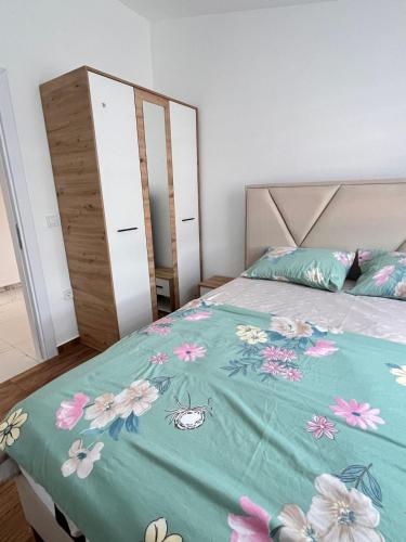 a bedroom with a bed with a blue blanket with flowers at Apartman Jana in Bar