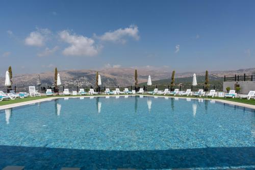 a large swimming pool with chairs and umbrellas at Maison Jwar - Charming Caravan Experience - Unique Summer Getaway in Jiwār al Ḩawz