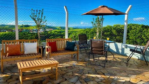 a patio with benches and a table and an umbrella at Pousada Vista Chic in Cunha