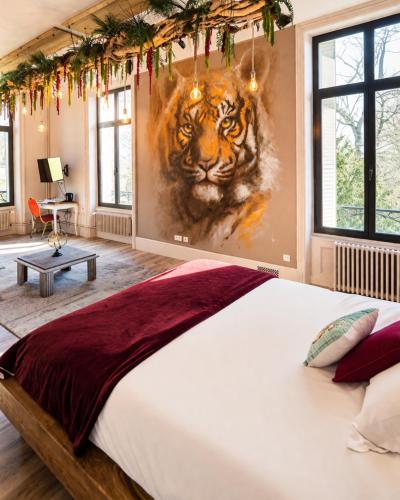 a bedroom with a large tiger painting on the wall at Manoir des Rêves Sauvages in Parentignat