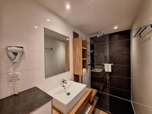 a bathroom with a sink and a shower at The Originals Boutique, Hôtel Les Strélitzias in Juan-les-Pins