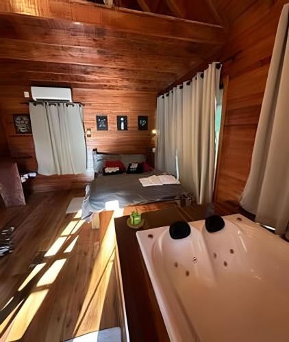 a room with two beds and a tub in a cabin at Cabana Bem-te-vi in Três Coroas