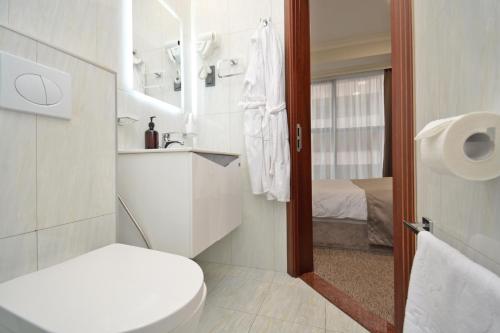 a white bathroom with a toilet and a sink at BM Avenue Hotel in Yerevan