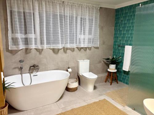 a bathroom with a white tub and a toilet at Sunset Cove in Plettenberg Bay