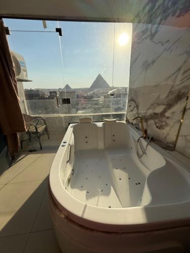 a bath tub in a bathroom with a view of the pyramids at Middle east panorama jacuzzi & spa in Cairo