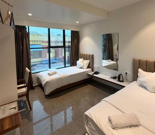a hotel room with two beds and a large window at Hotel Skyboat Inn in Nashik