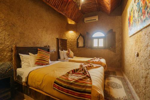 a bedroom with two beds and a window at Kasbah Hotel Tombouctou in Merzouga