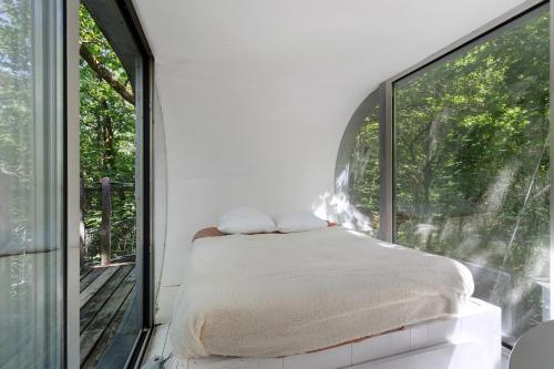 a bedroom with a bed and a large window at Cabane Le Module in Angoisse