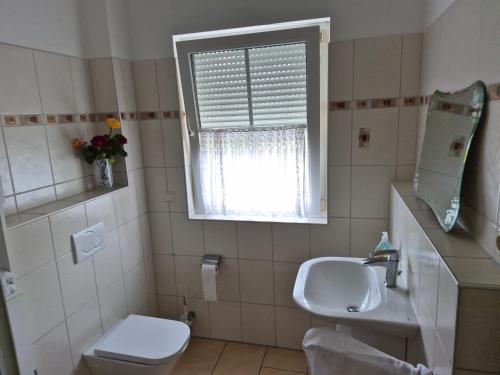 a bathroom with a sink and a toilet and a window at Sonniges Zimmer im Einfamilienhaus in Berlin