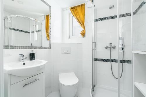a white bathroom with a shower and a sink at Słoneczne Domki in Rewal