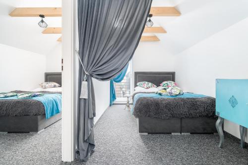 a bedroom with two beds and a curtain at Słoneczne Domki in Rewal