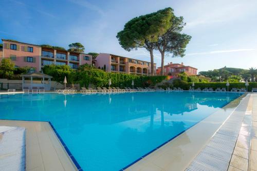 a large blue swimming pool with buildings in the background at Hôtel Les Jardins De Sainte-Maxime in Sainte-Maxime