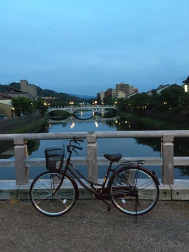 a bike parked on a bridge near a river at Kanazawa Guest House East Mountain in Kanazawa