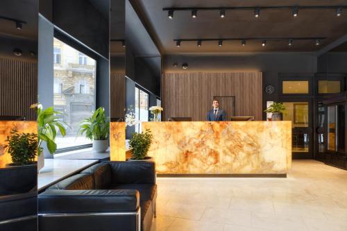 a man standing at a reception desk in a lobby at Hotel Harmony in Prague