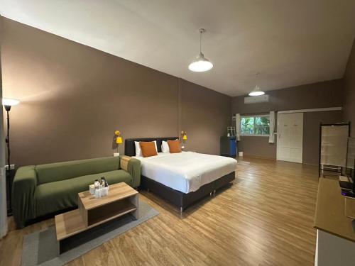 a bedroom with a bed and a green couch at Khao Yai Cottage in Mu Si