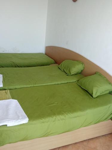 a bed with green sheets and pillows on it at Studio A in Sveti Vlas