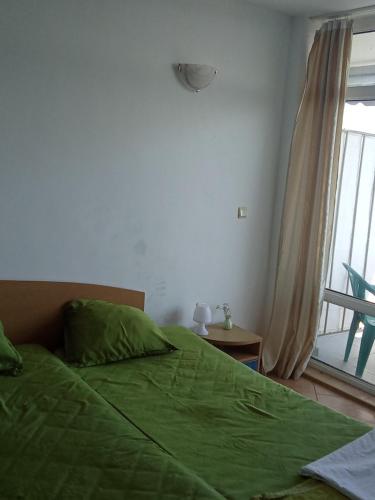 a bedroom with a green bed and a window at Studio A in Sveti Vlas