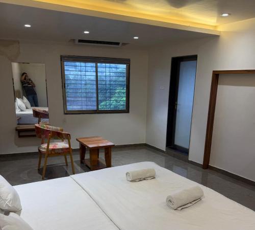 a bedroom with two beds and a table and a window at Hotel Skyboat Inn in Nashik