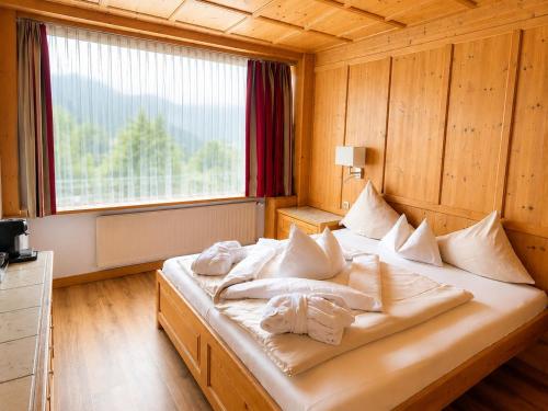 a bedroom with a bed with white pillows and a window at Hotel Latini in Zell am See