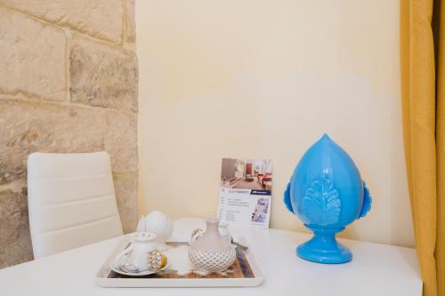 a table with a blue vase and a tray of dishes at Arco Suite - Lecce Selection in Lecce
