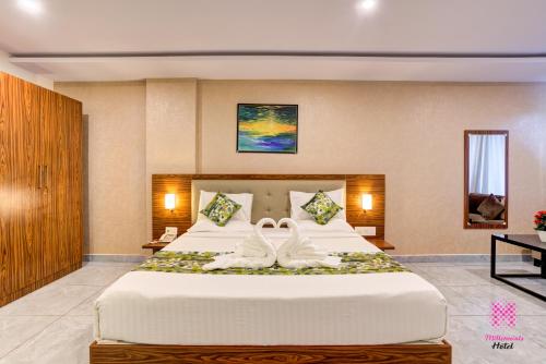 two white wedding shoes on a bed in a hotel room at Millennials Hotel in Kammasandra