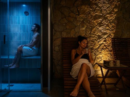a woman sitting on a bench in a bath room at SPA ROOM SICILIA - Suite con Spa ad uso esclusivo Jacuzzi Sauna Hammam in Rosolini