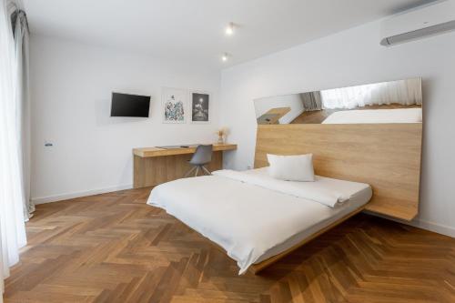 a white bedroom with a bed and a desk at Aparthotel Blend City Center in Bucharest