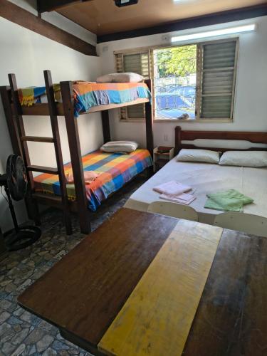 a room with two bunk beds and a table at Sunset House Lofts Caragua in Caraguatatuba