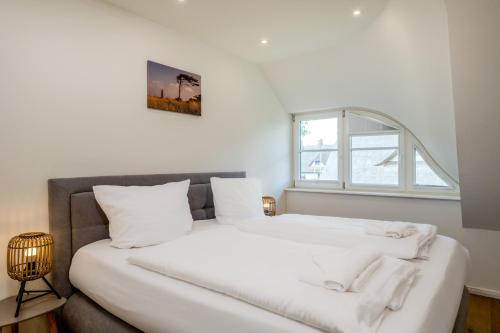 a bedroom with a large white bed with a window at Jade 1 in Born