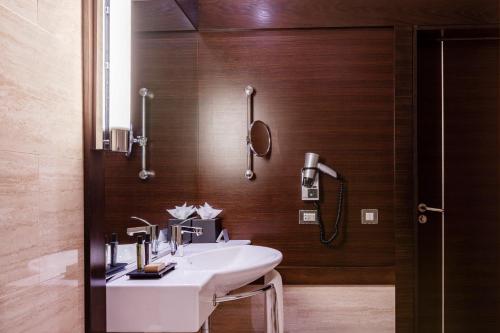 een badkamer met een witte wastafel en houten wanden bij BessaHotel Boavista in Porto