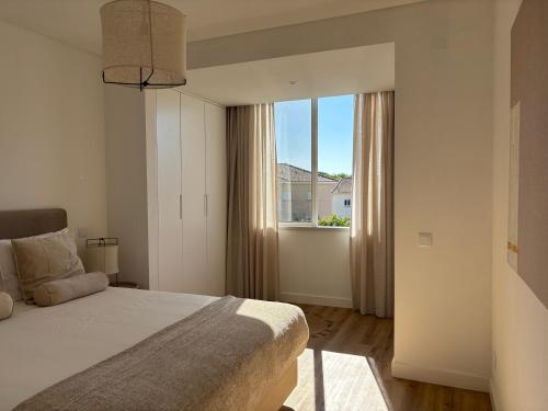 a bedroom with a bed and a large window at Vila apartment, free parking in Cascais