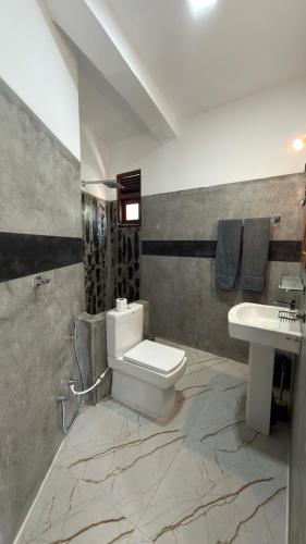 a bathroom with a white toilet and a sink at Induwara Villa in Ahungalla