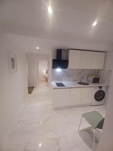 a kitchen with white cabinets and a green chair at Flor do Padrão in Elvas