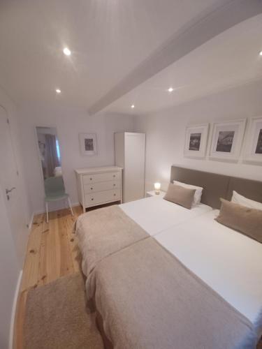 a white bedroom with a large bed and a dresser at Flor do Padrão in Elvas