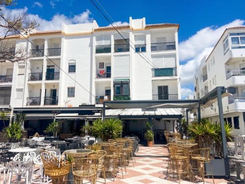 an outdoor patio with tables and chairs in front of a building at Spacious Apartment in Barbate - Terrace with Sea View in Barbate