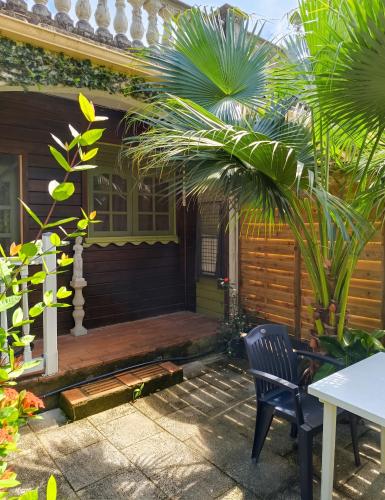 a porch of a house with a bench and palm trees at Studio confortable à Schoelcher - 16 m² - Jardin privé in Schœlcher