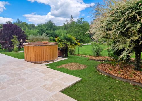 a garden with a wooden barrel in the grass at Villa de charme à Ribérac avec piscine privée in Ribérac