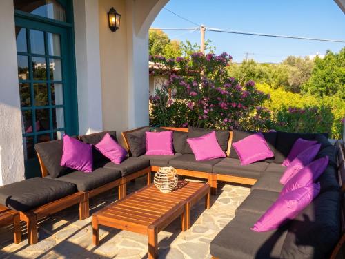 a couch with pink pillows on a patio at Picturesque Villa in Limnos + Enclosed Garden + Sea View in Lemnos