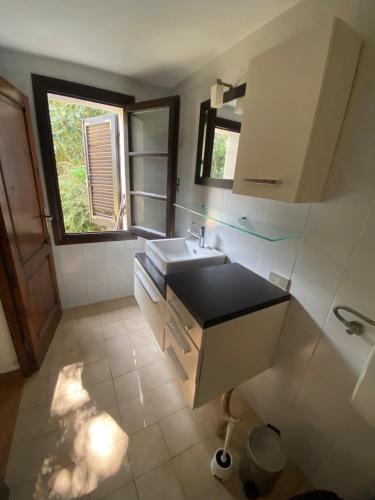 a white bathroom with a sink and a window at Atelier Suvereto in Suvereto