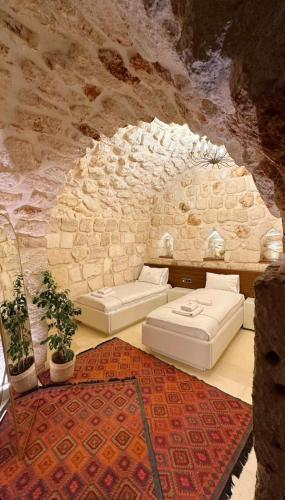 two beds in a room with a stone wall at Konak Zenobia in Midyat