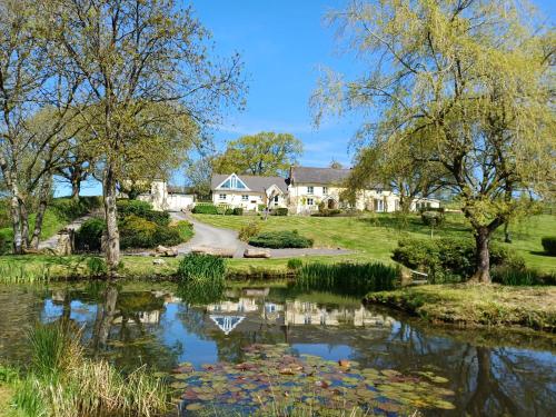 a house with a pond in front of it at The Old Dairy With Indoor Pool In Devon in Broadwoodkelly