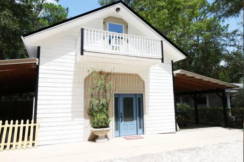 a small white building with a balcony and a blue door at Charming Oasis - Ultimate Rustic Getaway! in St. Augustine