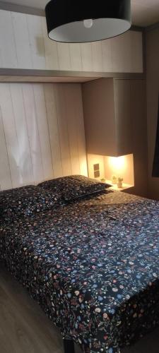 a bedroom with a large bed with a floral blanket at Chalet HABIA TXIKIA 4 pers, neuf, sur Hasparren, calme, avec piscine et climatisation, Pays Basque in Hasparren