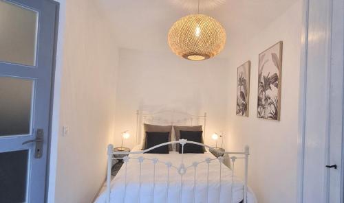 a bedroom with a bed and a chandelier at LE BAYARD Authentique Maison Sétoise Patio Climatisée Centre Historique Parking payant à proximité in Sète