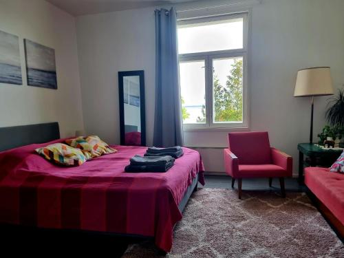 a bedroom with a bed and a chair and a window at Pispalan Helmi - Koti Näköalalla in Tampere