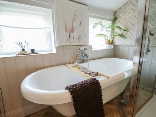a bathroom with a tub and a window at Pax Cottage in Beccles