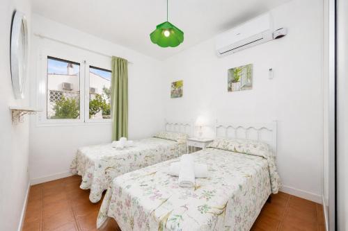 two beds in a white room with two windows at Villa Mares in Cala en Porter