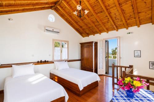 two beds in a room with wooden ceilings at Villa Antigoni in Alikias