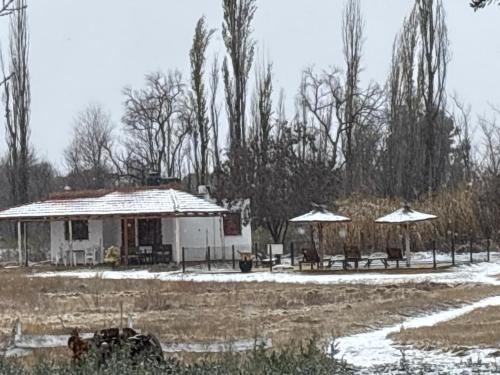 a house with tables and umbrellas in the snow at CABAÑAS LA PILARICA in San Rafael